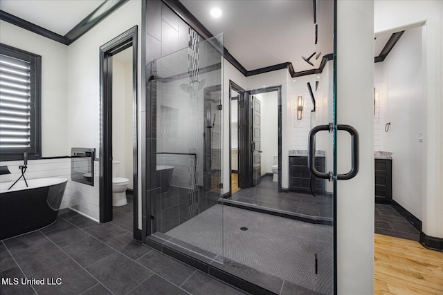 bathroom with ornamental molding, a freestanding bath, toilet, and a shower stall