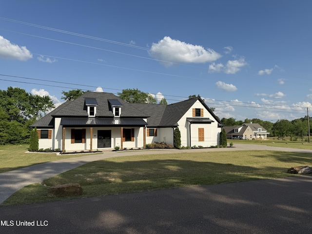 modern farmhouse style home featuring covered porch, a front yard, and a standing seam roof