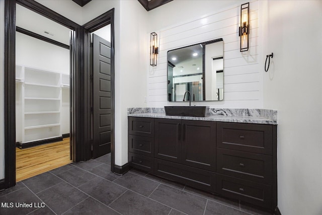 bathroom with vanity, tile patterned flooring, baseboards, and a spacious closet