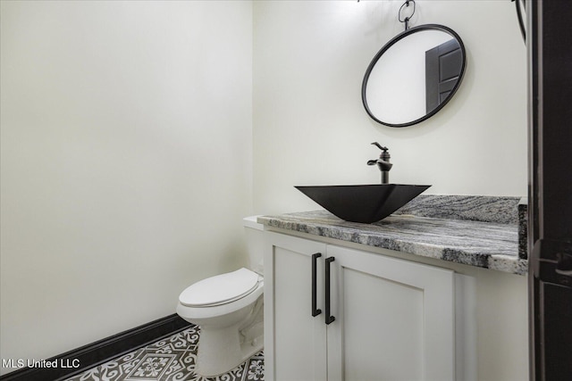 half bathroom featuring vanity, tile patterned flooring, and toilet