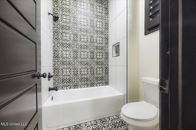 bathroom featuring washtub / shower combination, tile patterned flooring, and toilet