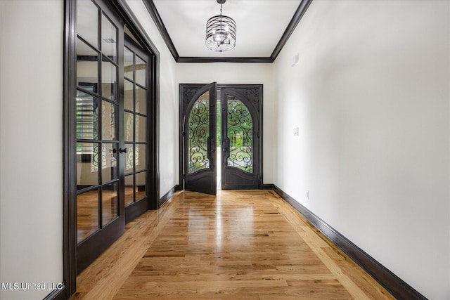 doorway to outside featuring baseboards, ornamental molding, french doors, and light wood-style flooring