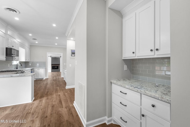 112 Louis Wilson Dr, Brandon, MS 39042 - kitchen featuring decorative backsplash, wood finished floors, white cabinetry, light stone counters, and crown molding