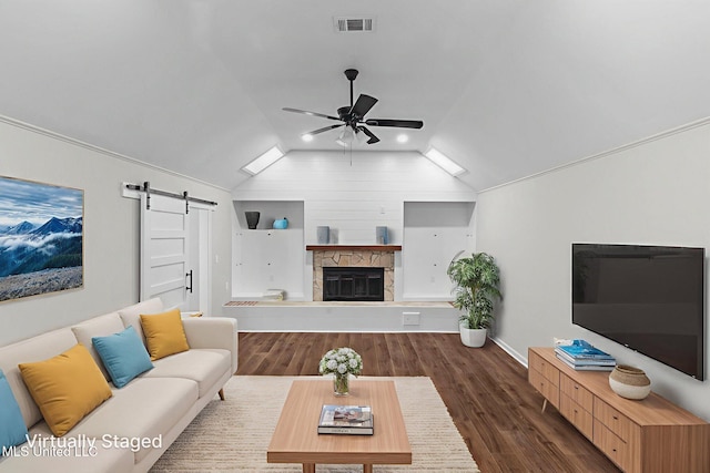 112 Louis Wilson Dr, Brandon, MS 39042 - living area featuring a barn door, ceiling fan, vaulted ceiling, dark wood-style floors, and a stone fireplace