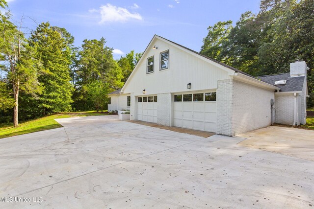 112 Louis Wilson Dr, Brandon, MS 39042 - view of home's exterior with a garage, brick siding, concrete driveway, a chimney, and a shingled roof
