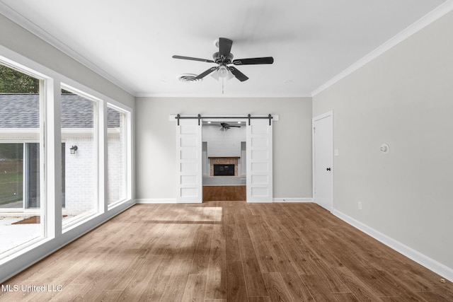 112 Louis Wilson Dr, Brandon, MS 39042 - unfurnished living room featuring wood finished floors, ceiling fan, healthy amount of natural light, ornamental molding, and a barn door