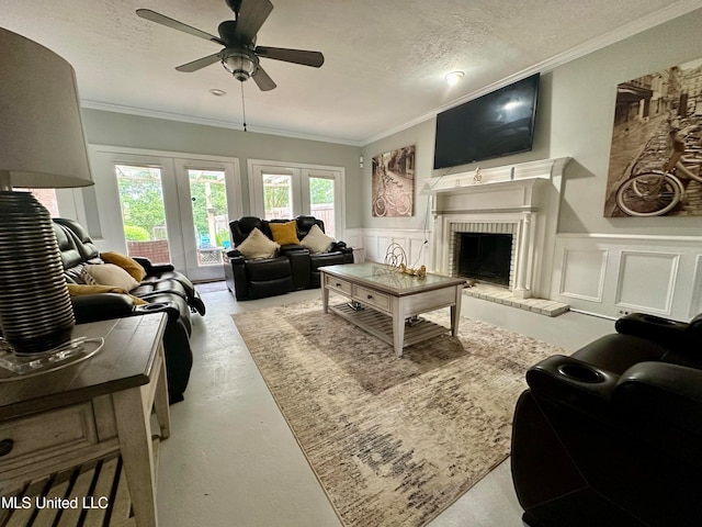 living room featuring french doors, ornamental molding, a textured ceiling, and a brick fireplace