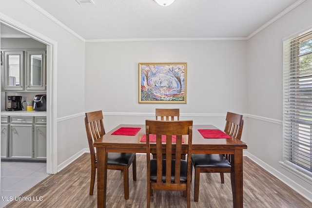 dining space featuring crown molding, baseboards, and light wood-style flooring