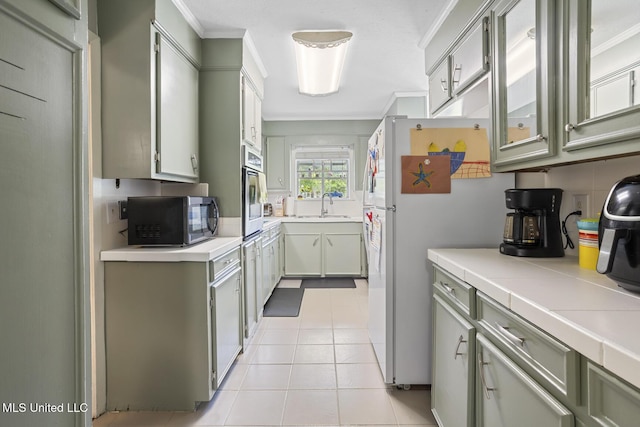 kitchen with crown molding, a sink, stainless steel microwave, light tile patterned floors, and tasteful backsplash