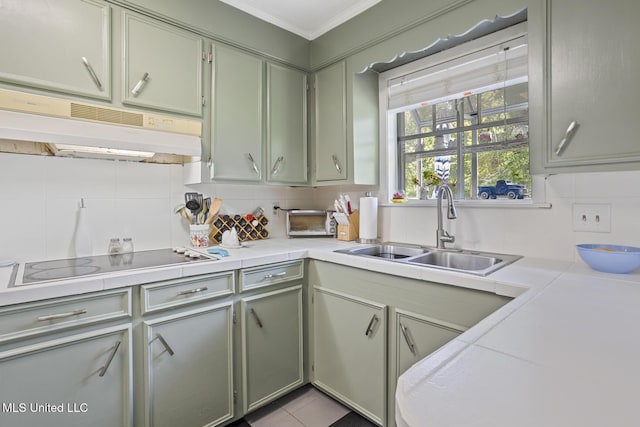 kitchen featuring a sink, tasteful backsplash, under cabinet range hood, and black electric cooktop