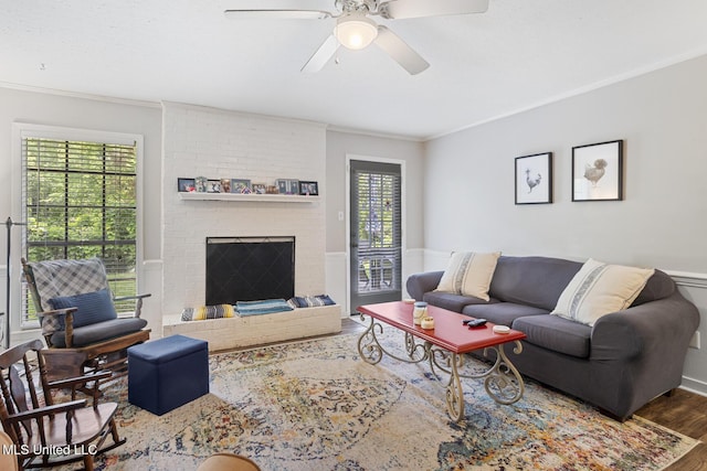 living room featuring ceiling fan, ornamental molding, wood finished floors, and a wainscoted wall