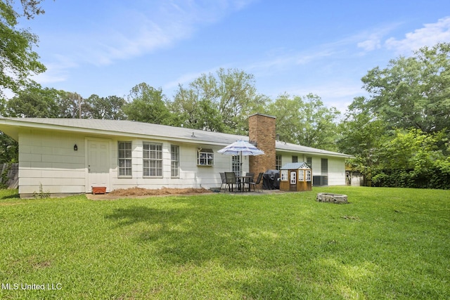 rear view of property with a patio area, a yard, and a chimney