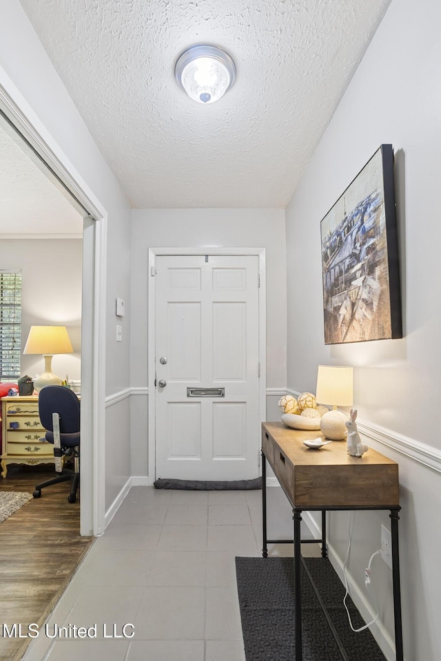 entryway with light tile patterned floors, baseboards, and a textured ceiling