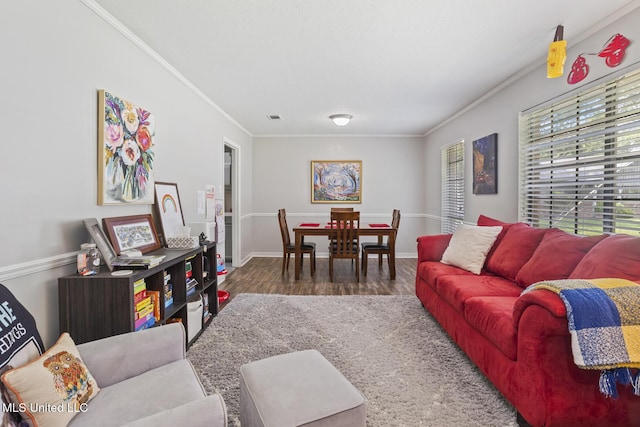 living room featuring crown molding, baseboards, wood finished floors, and visible vents