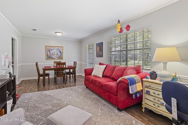 living room featuring baseboards, ornamental molding, wood finished floors, and visible vents