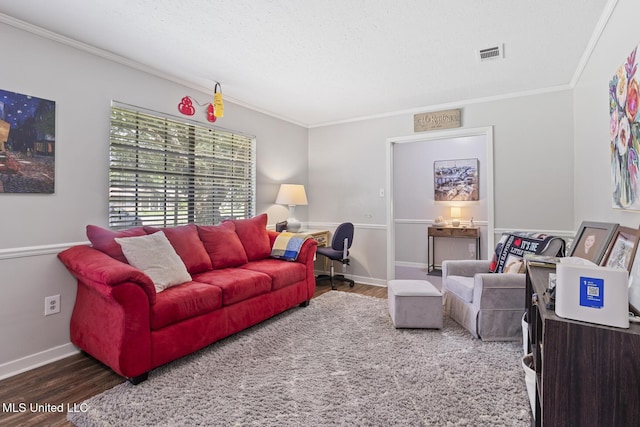 living room with visible vents, baseboards, crown molding, and wood finished floors