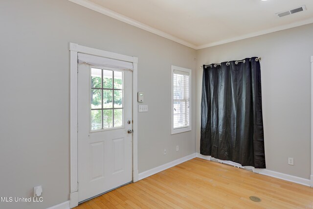 doorway to outside featuring baseboards, light wood-type flooring, crown molding, and visible vents