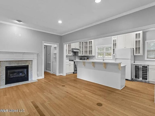 kitchen with light countertops, freestanding refrigerator, beverage cooler, and under cabinet range hood