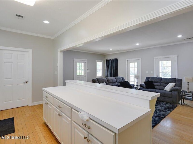 kitchen featuring light wood finished floors, visible vents, crown molding, and a kitchen island