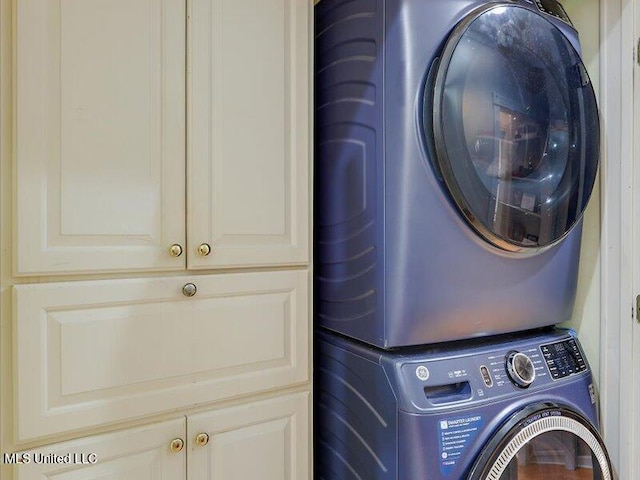 clothes washing area with stacked washer / dryer and cabinet space
