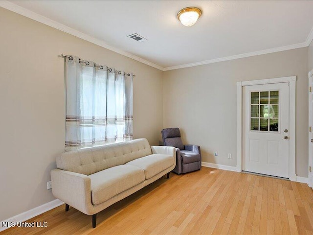 living area featuring crown molding, visible vents, light wood-style flooring, and baseboards