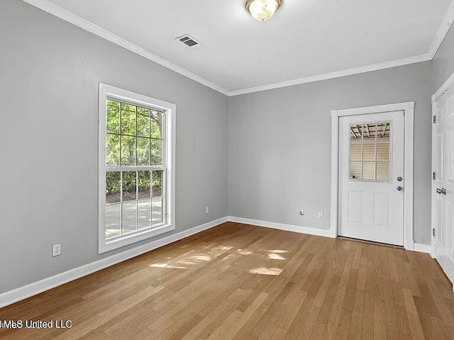 empty room with wood finished floors, baseboards, ornamental molding, and visible vents