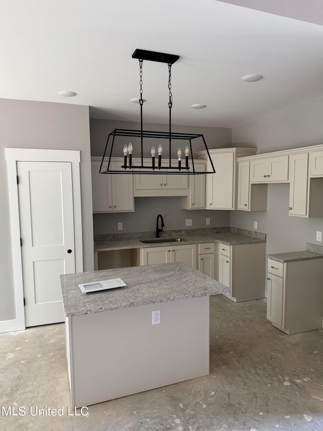 kitchen featuring sink, a center island, white cabinetry, decorative light fixtures, and a chandelier