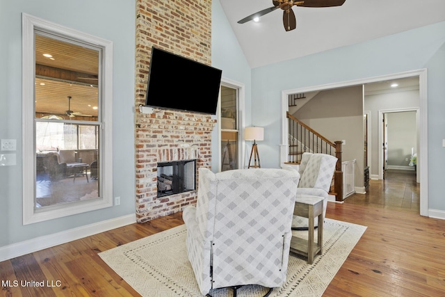 living area with hardwood / wood-style flooring, a fireplace, stairway, and a ceiling fan