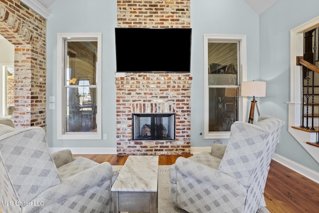 living room with lofted ceiling, a fireplace, baseboards, and wood finished floors