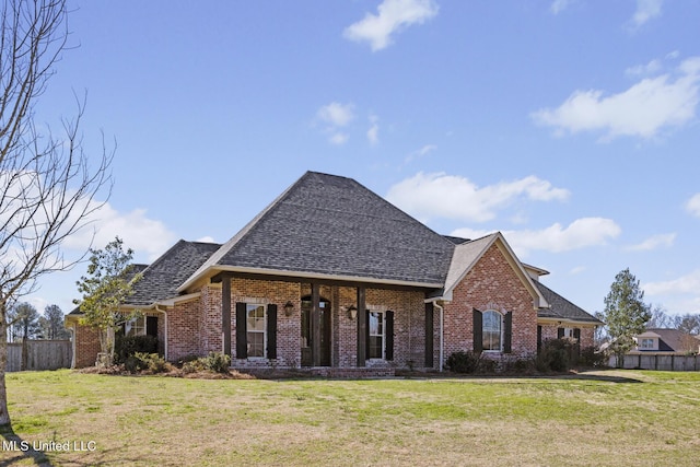 view of front of property with a shingled roof, a front yard, brick siding, and fence