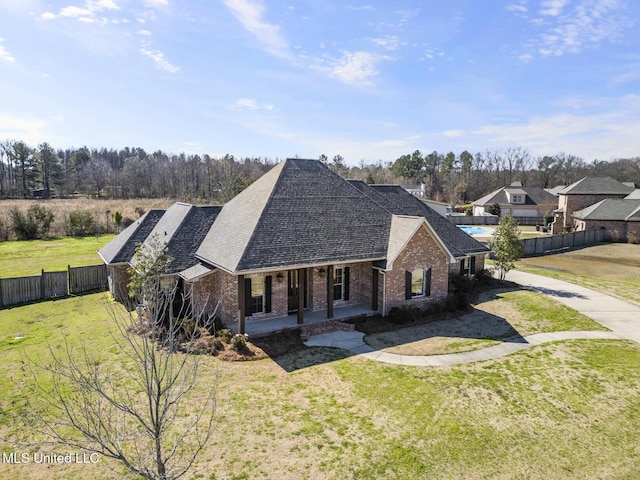 view of front of house featuring brick siding, a front yard, fence, and a shingled roof