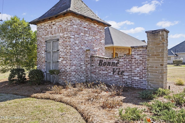 view of side of home featuring brick siding and a high end roof