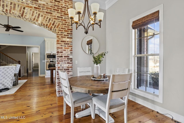 dining space featuring light wood finished floors, baseboards, and ceiling fan with notable chandelier