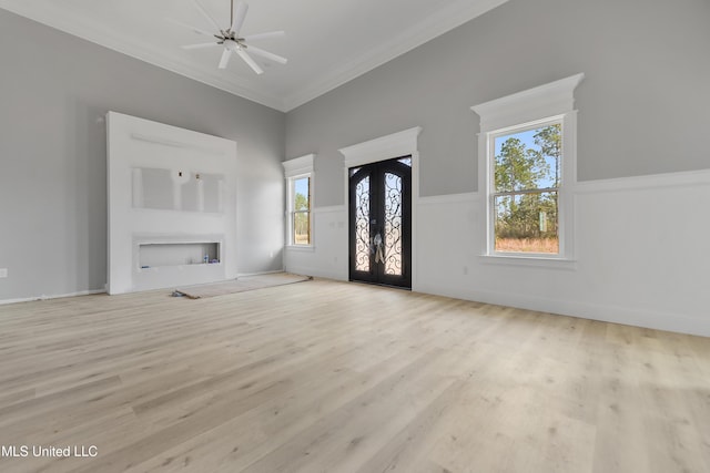 unfurnished living room featuring crown molding, a healthy amount of sunlight, light hardwood / wood-style floors, and french doors