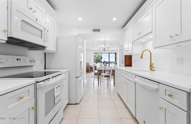 kitchen featuring white appliances, light tile patterned flooring, sink, white cabinets, and a chandelier