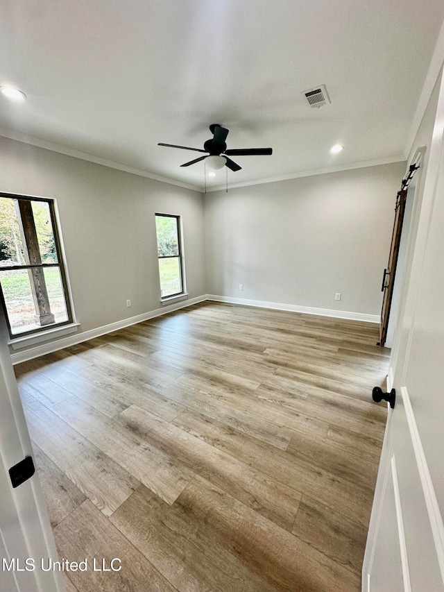 empty room featuring ceiling fan, crown molding, and light wood-type flooring