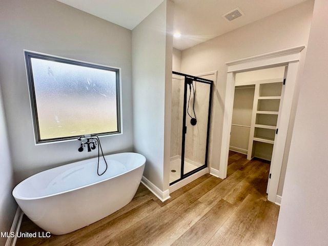 bathroom with independent shower and bath and wood-type flooring