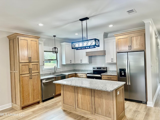 kitchen featuring a kitchen island, stainless steel appliances, decorative light fixtures, light wood-type flooring, and white cabinets