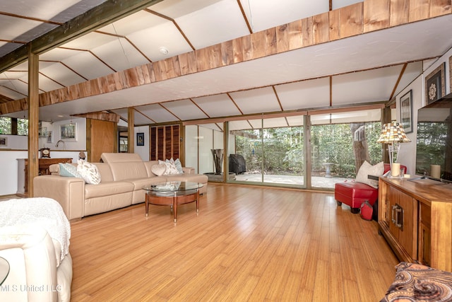 living room with expansive windows, lofted ceiling with beams, and light wood finished floors