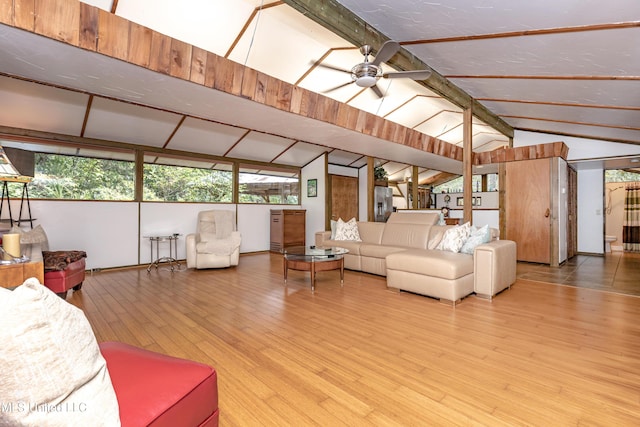 living room featuring baseboards, a ceiling fan, wood finished floors, and vaulted ceiling with beams