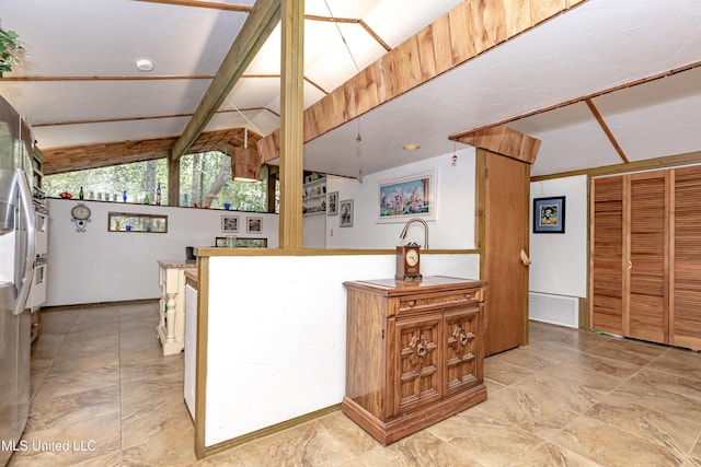 kitchen featuring lofted ceiling, visible vents, and freestanding refrigerator