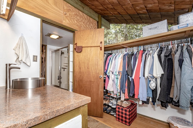 walk in closet with wood finished floors and a sink