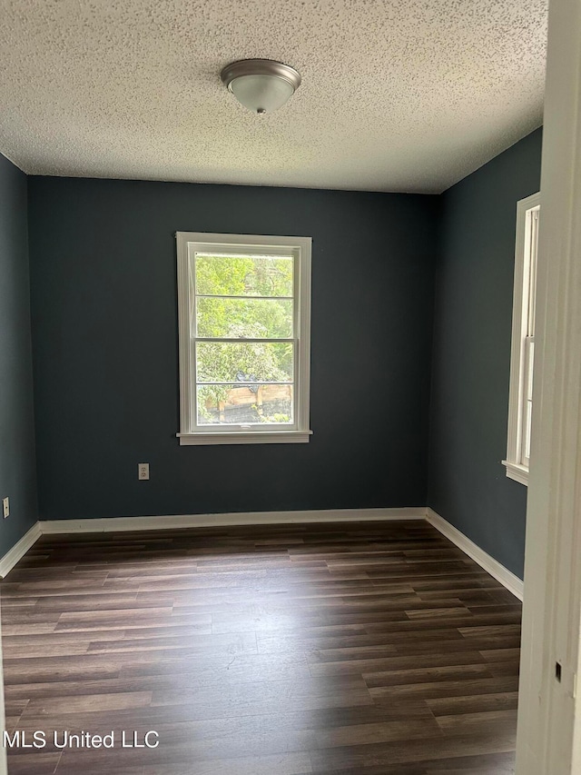 empty room featuring a textured ceiling and dark hardwood / wood-style floors