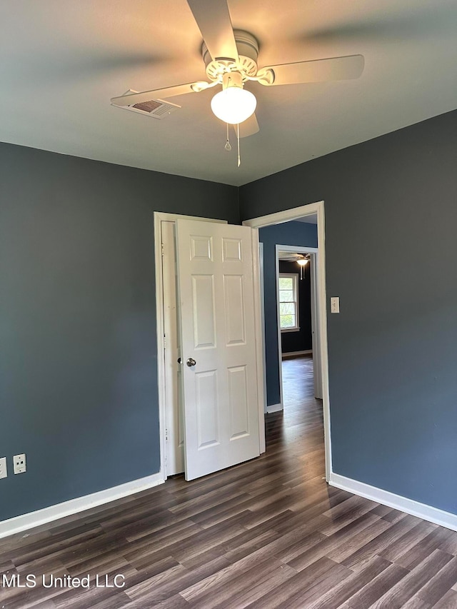 unfurnished room featuring dark wood-type flooring and ceiling fan