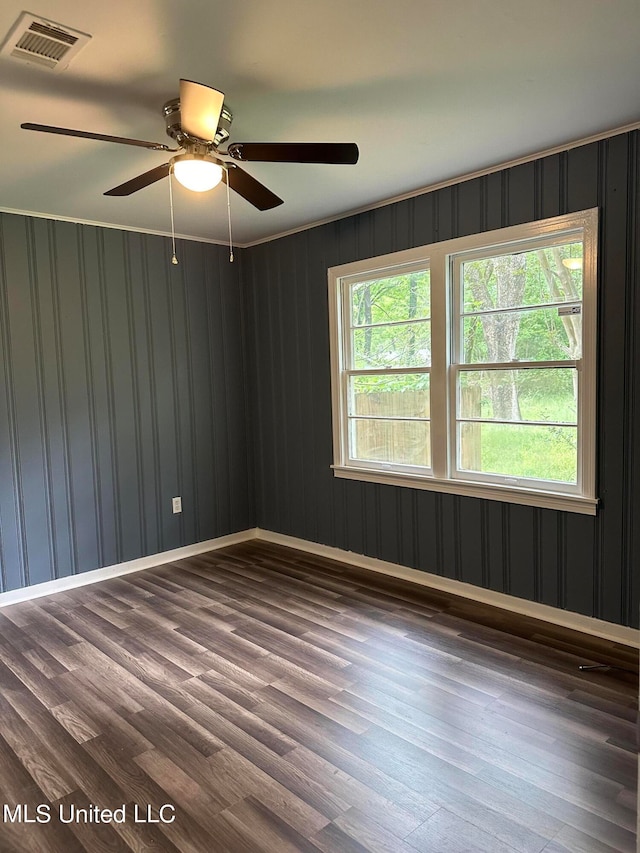 unfurnished room featuring ceiling fan, wood walls, and dark hardwood / wood-style floors