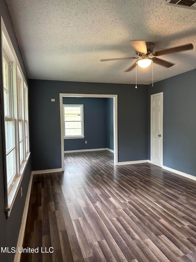 spare room featuring dark wood-type flooring, ceiling fan, and a textured ceiling