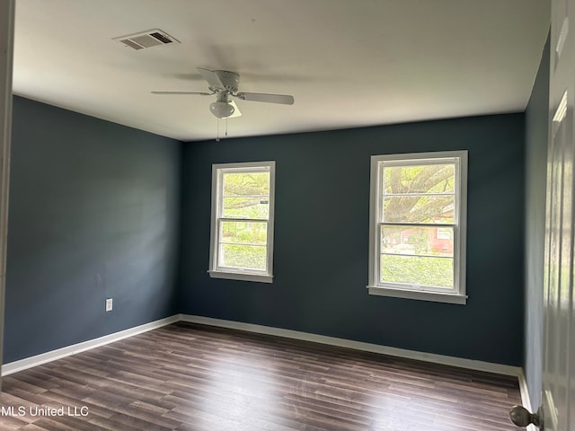 empty room featuring ceiling fan, a healthy amount of sunlight, and dark hardwood / wood-style flooring