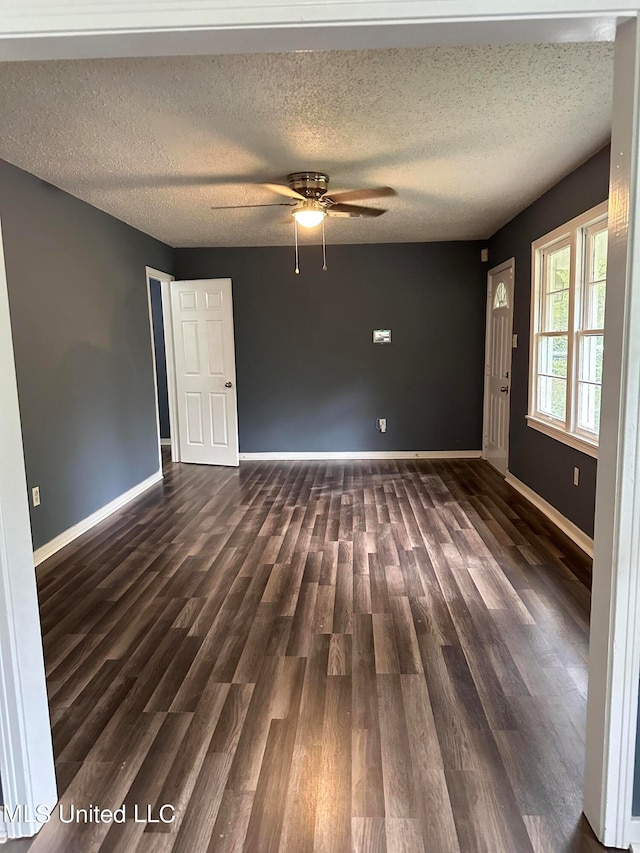 unfurnished room with dark wood-type flooring, ceiling fan, and a textured ceiling