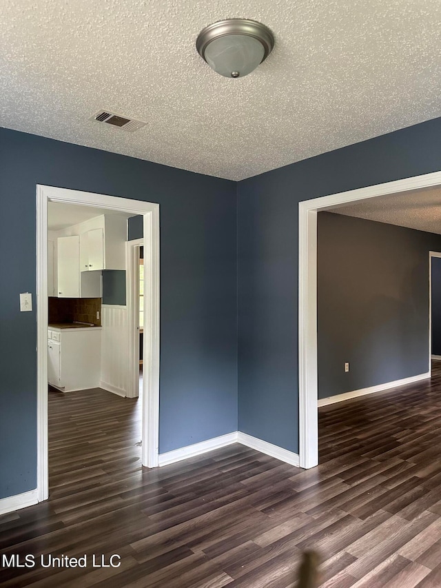 unfurnished room with dark wood-type flooring and a textured ceiling