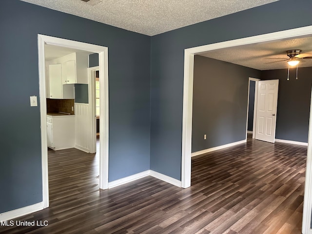 empty room with ceiling fan, a textured ceiling, and dark hardwood / wood-style floors